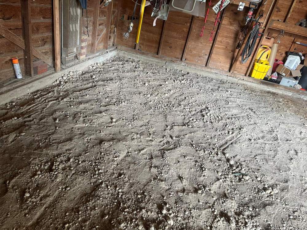 Old garage with a bare dirt and gravel floor