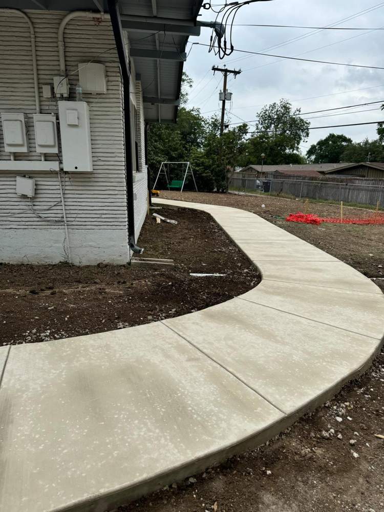 Finished curved concrete sidewalk beside a house